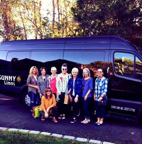 A group of people standing in front of a black van.