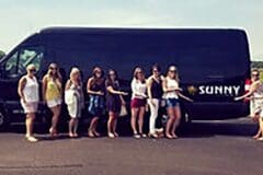 A group of women standing next to a black bus.