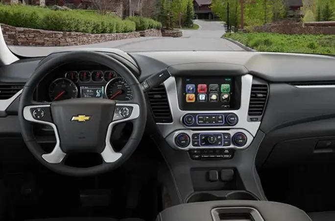 A dashboard of a car with the steering wheel and infotainment system.
