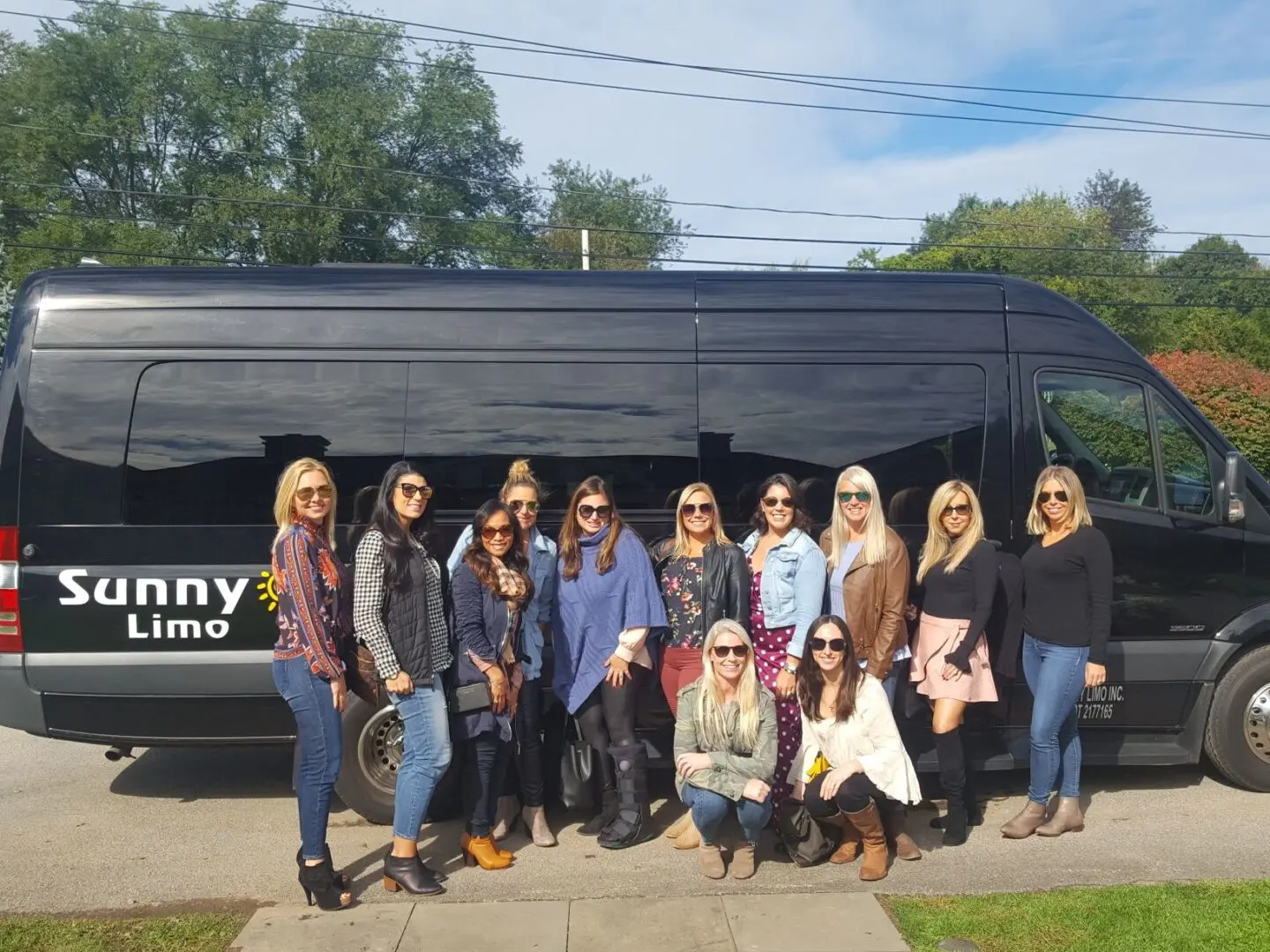 A group of women standing in front of a black limo.