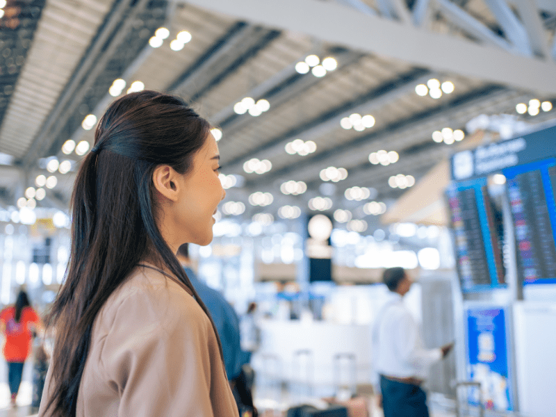 Young woman viewing airport departure board