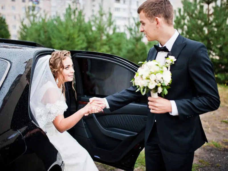 Newly wed couple exiting a black limo